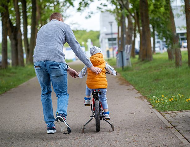 man teaching young person how to ride a bike